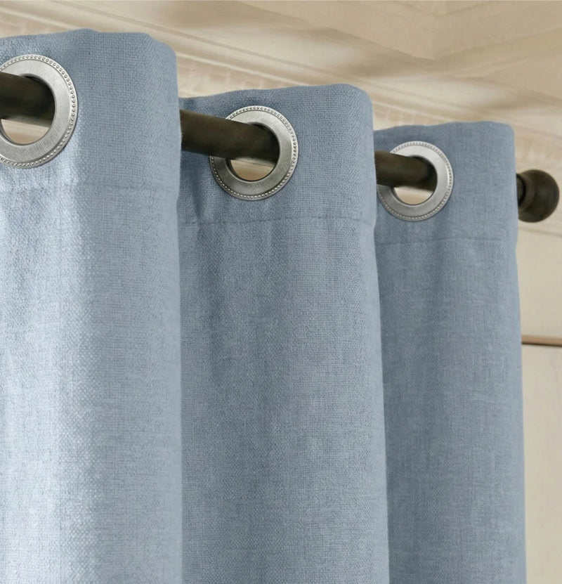 Made-to-measure Qurtens blue blackout thermal acoustic curtain heading with silver metal eyelets on a black pole, close-up of the thick-cloth hang